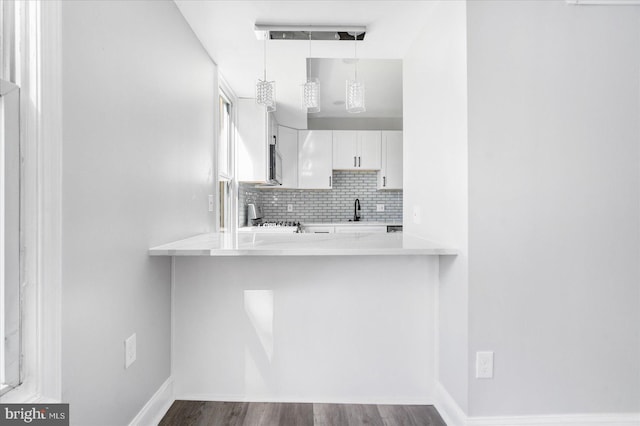 kitchen featuring stainless steel appliances, backsplash, hardwood / wood-style floors, white cabinets, and pendant lighting