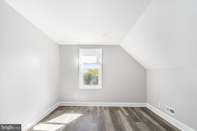 additional living space with dark wood-type flooring and vaulted ceiling