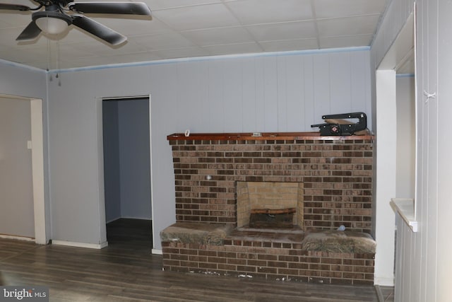 unfurnished living room with dark hardwood / wood-style flooring, a paneled ceiling, wooden walls, and ceiling fan