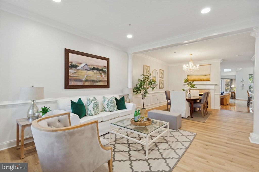 living room with ornamental molding, light wood-type flooring, and an inviting chandelier