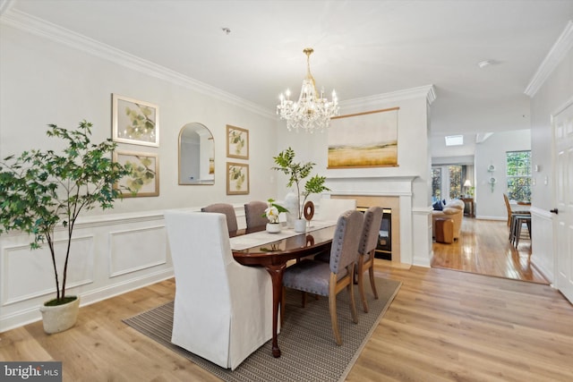 dining space with ornamental molding, light hardwood / wood-style flooring, and a notable chandelier