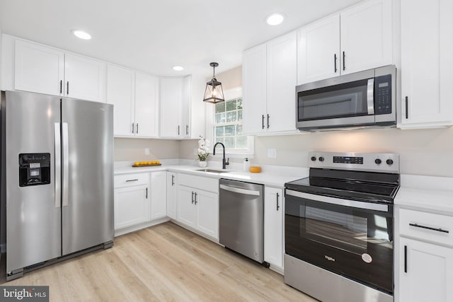 kitchen with white cabinetry, appliances with stainless steel finishes, sink, and light hardwood / wood-style flooring