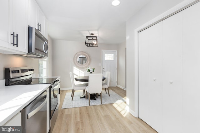 kitchen featuring white cabinets, stainless steel appliances, light hardwood / wood-style floors, and plenty of natural light