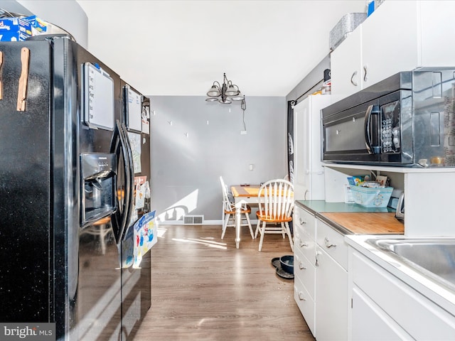 kitchen with light wood-type flooring, white cabinetry, and black appliances