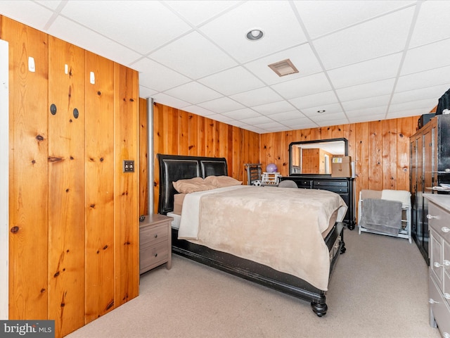 carpeted bedroom featuring a paneled ceiling and wooden walls