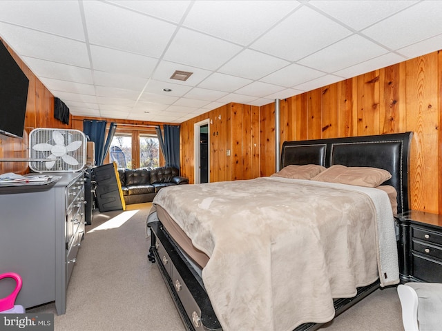 bedroom with wooden walls, a drop ceiling, and carpet