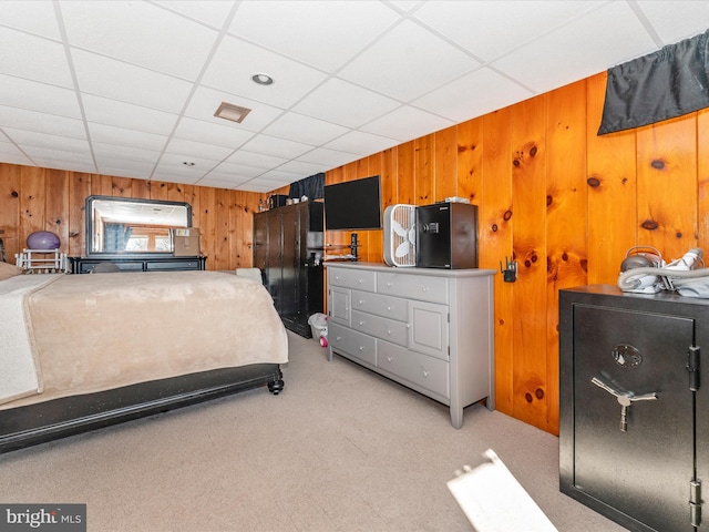 carpeted bedroom with wood walls and a drop ceiling