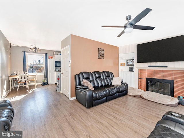 living room featuring ceiling fan with notable chandelier and light hardwood / wood-style floors