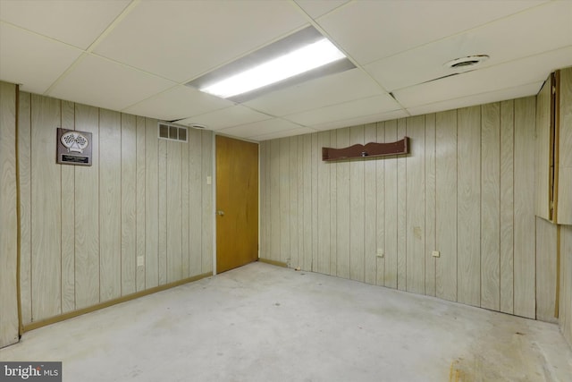 basement with a paneled ceiling and wood walls