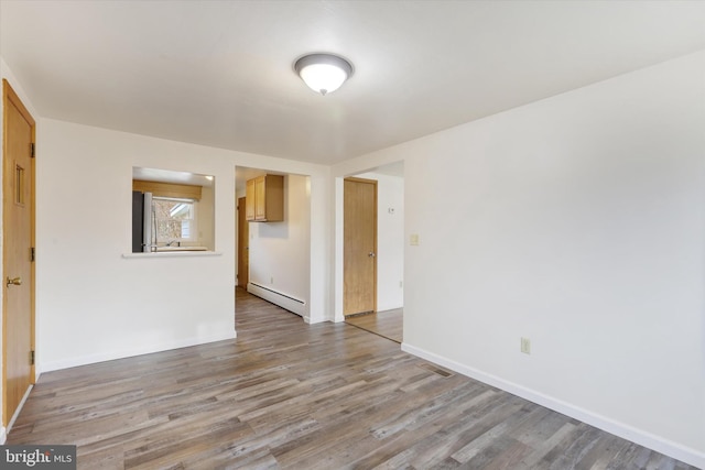 spare room featuring hardwood / wood-style floors and a baseboard heating unit