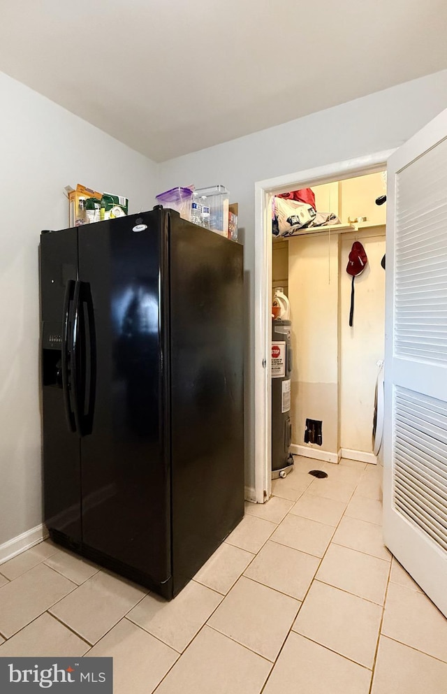 kitchen featuring black fridge, water heater, and light tile patterned flooring