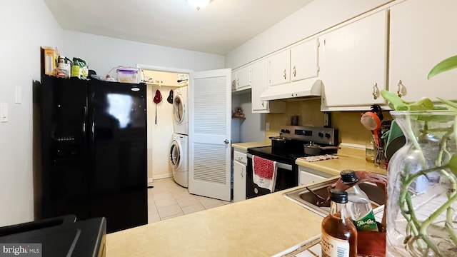 kitchen featuring stacked washing maching and dryer, black fridge, electric stove, white cabinets, and light tile patterned flooring