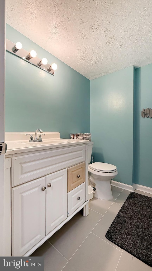 bathroom with tile patterned floors, vanity, toilet, and a textured ceiling