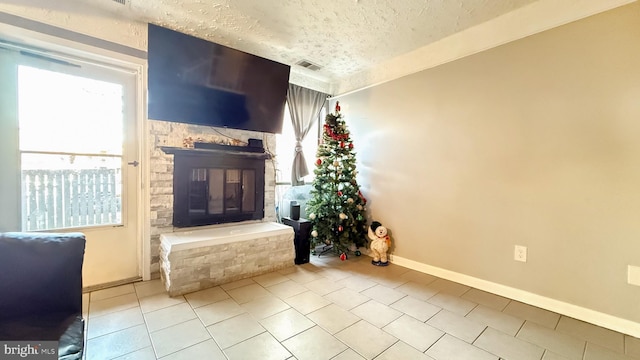 unfurnished living room with a fireplace, light tile patterned flooring, and a textured ceiling