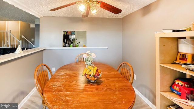 tiled dining space featuring ceiling fan and a textured ceiling