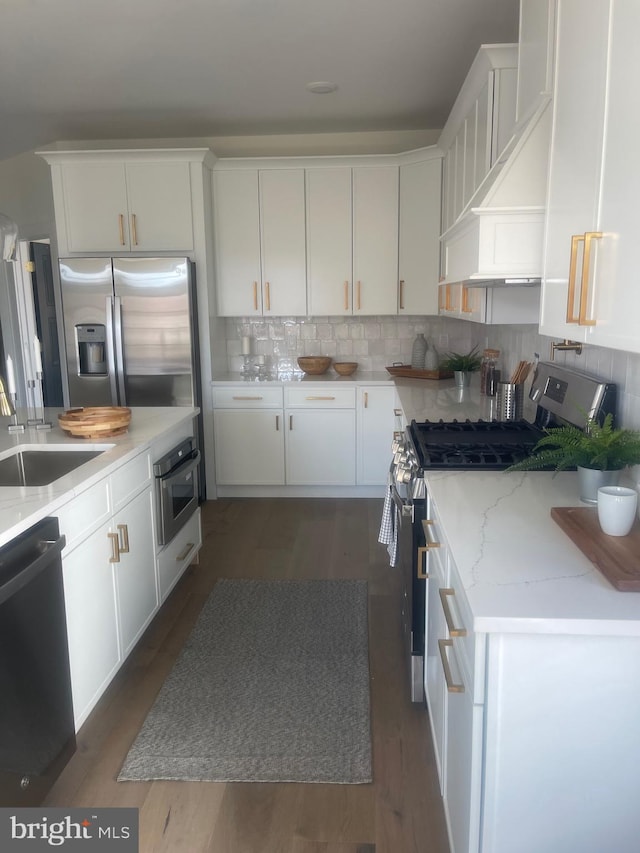 kitchen featuring wall chimney range hood, white cabinetry, stainless steel appliances, and sink