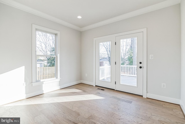 entryway featuring a wealth of natural light, crown molding, and light hardwood / wood-style flooring