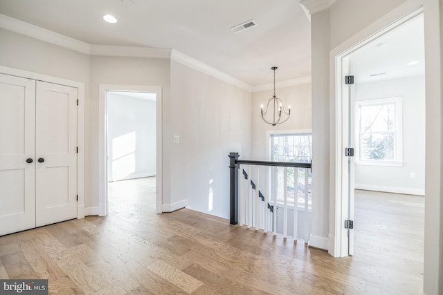 interior space with an inviting chandelier, light hardwood / wood-style flooring, and crown molding