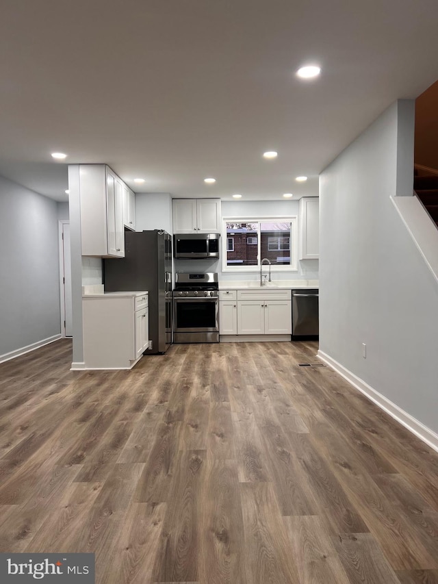 kitchen with white cabinets, wood-type flooring, stainless steel appliances, and sink