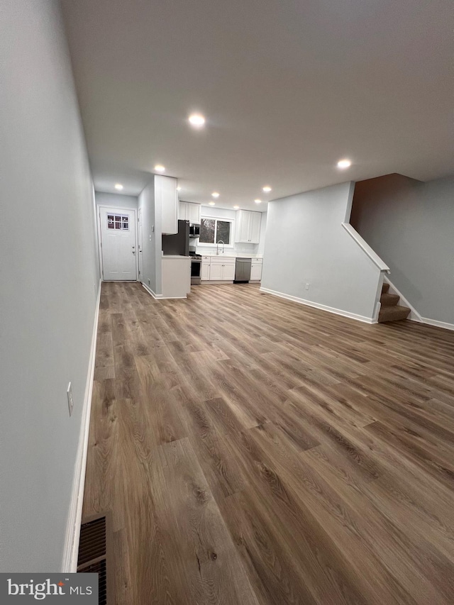 unfurnished living room featuring hardwood / wood-style floors and sink