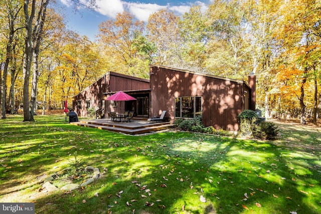 back of property with a lawn and a wooden deck