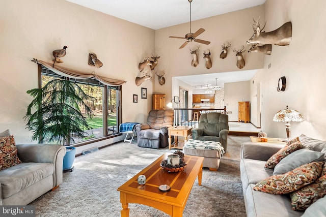 carpeted living room with high vaulted ceiling and ceiling fan with notable chandelier