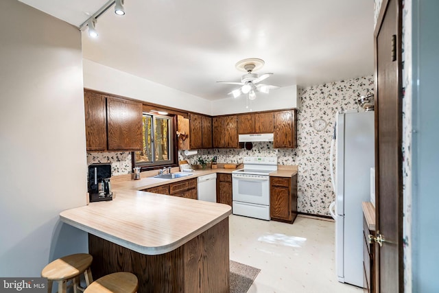 kitchen with kitchen peninsula, sink, rail lighting, ceiling fan, and white appliances