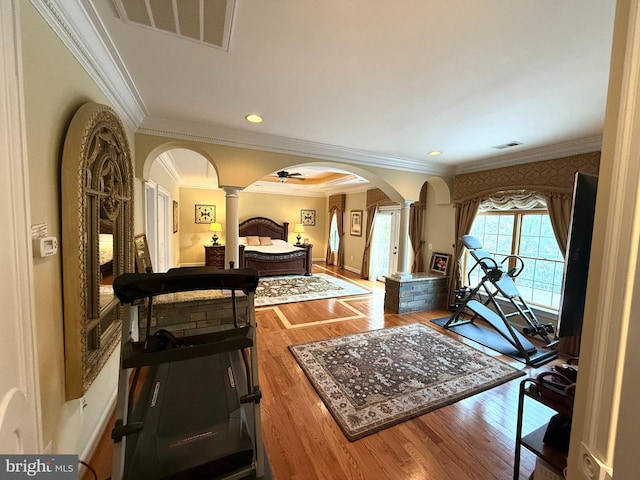 interior space featuring wood-type flooring, ornate columns, and crown molding