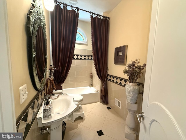 bathroom featuring tile patterned floors, shower / bath combo, tile walls, and toilet