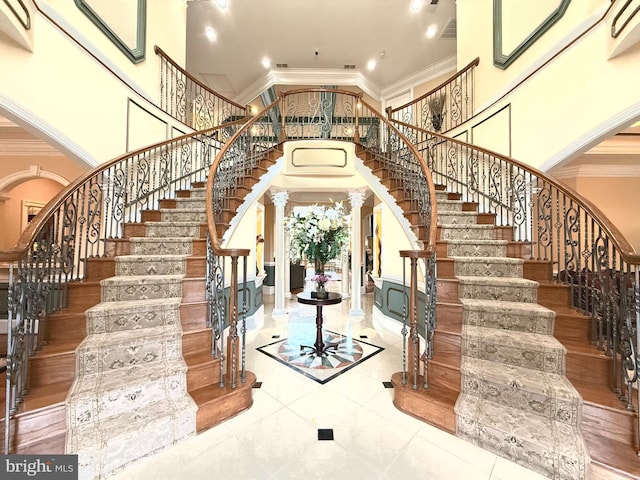 entryway with a towering ceiling, ornamental molding, and decorative columns