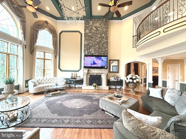 living room with ceiling fan, a high ceiling, wood-type flooring, and ornate columns