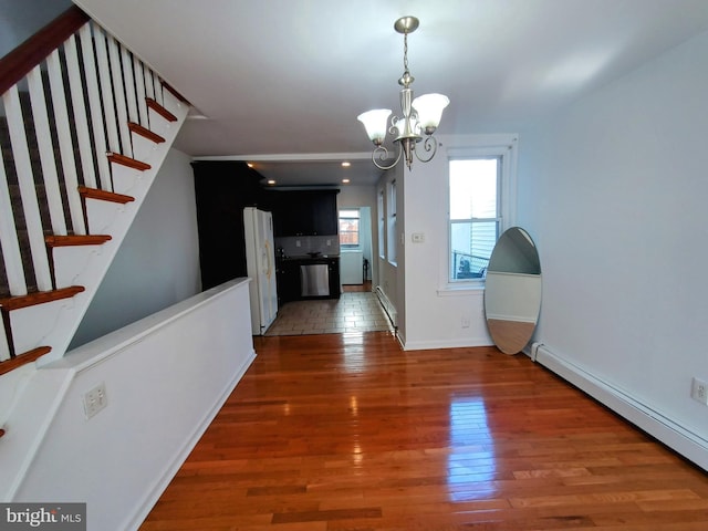 unfurnished dining area featuring dark wood-type flooring, baseboard heating, and a notable chandelier