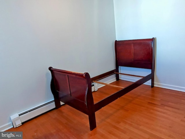 bedroom with hardwood / wood-style flooring and baseboard heating