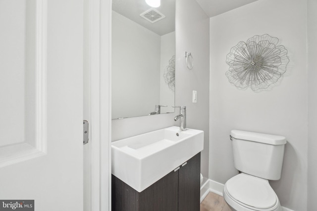 bathroom featuring toilet, vanity, and hardwood / wood-style flooring