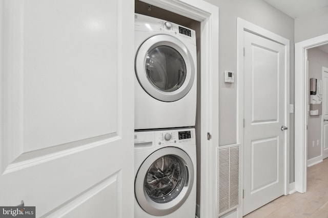 washroom with light wood-type flooring and stacked washer / dryer