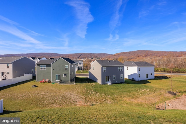 rear view of house with a mountain view and a yard