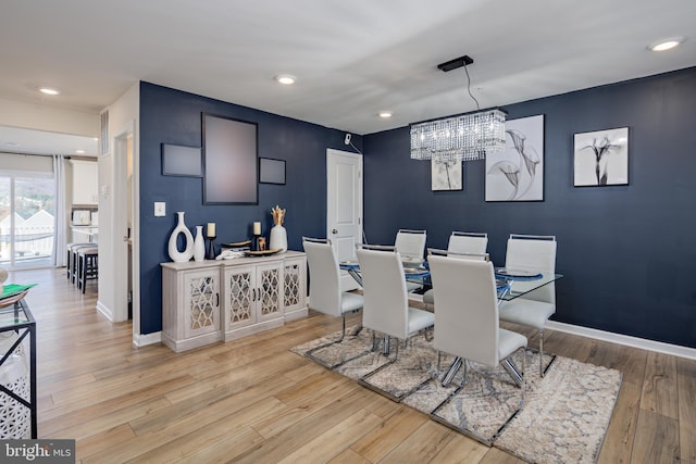 dining room with light hardwood / wood-style floors and a notable chandelier