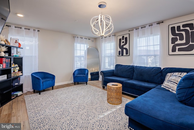 living room featuring a wealth of natural light, wood-type flooring, and a notable chandelier