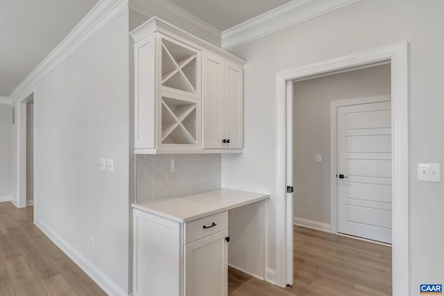 bar featuring white cabinetry, backsplash, crown molding, and light hardwood / wood-style flooring