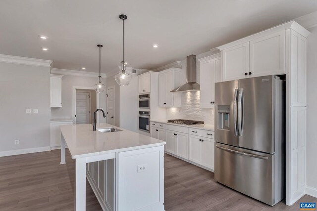 kitchen featuring sink, appliances with stainless steel finishes, an island with sink, wall chimney range hood, and pendant lighting