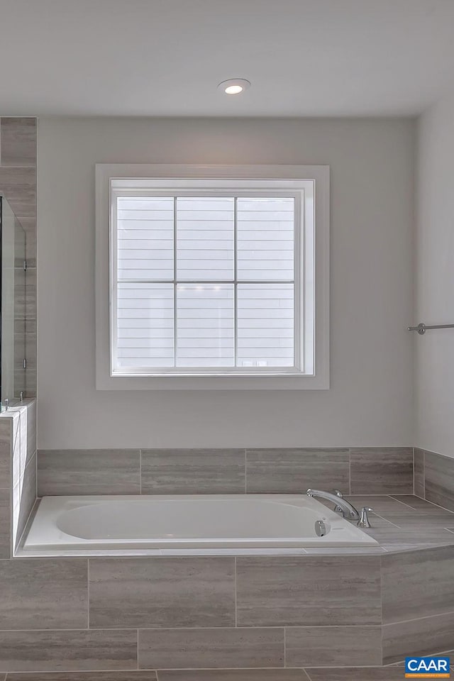 bathroom featuring plenty of natural light and a relaxing tiled tub