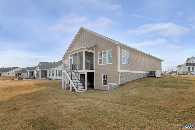 back of property with a lawn, a sunroom, and central AC