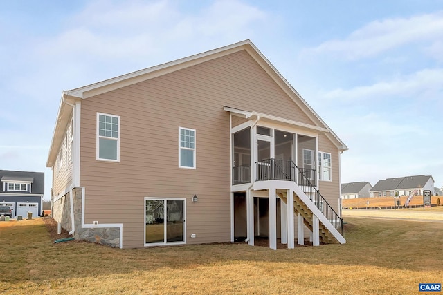 back of house featuring a lawn and a sunroom