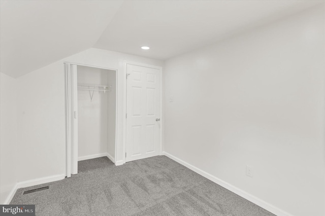 unfurnished bedroom featuring carpet flooring, a closet, and lofted ceiling