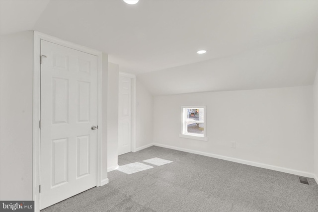 bonus room with lofted ceiling and light carpet