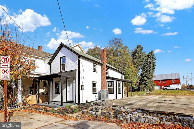 rear view of property featuring central AC unit and a porch