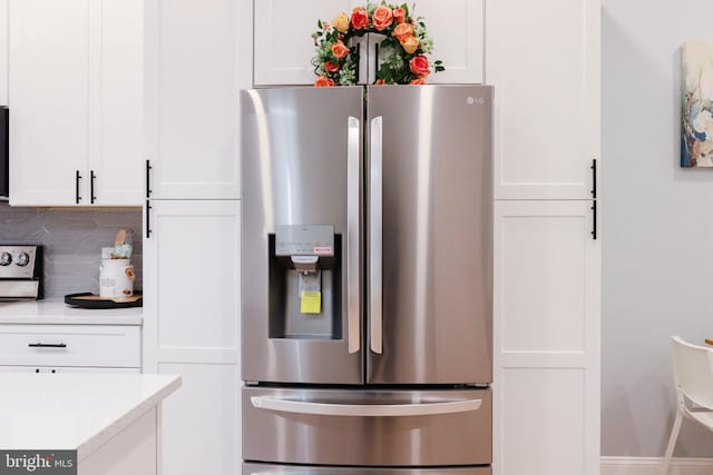 kitchen featuring decorative backsplash, stainless steel fridge with ice dispenser, and white cabinets