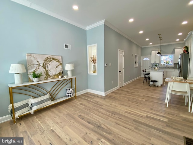 foyer featuring ornamental molding, sink, and light wood-type flooring