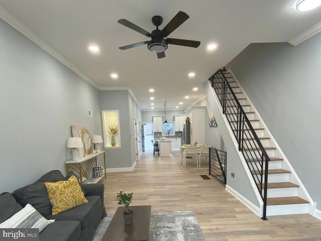 living room with ceiling fan, ornamental molding, and light wood-type flooring