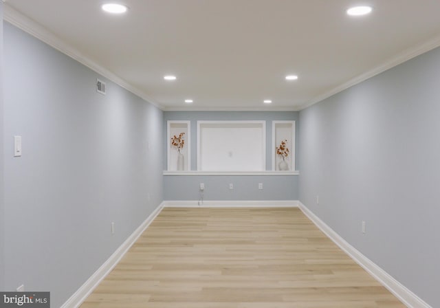 spare room featuring crown molding and light hardwood / wood-style floors